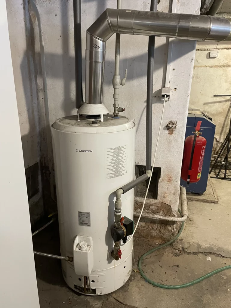 Zásobník teplé vody s instalovaným potrubím a hasicím přístrojem