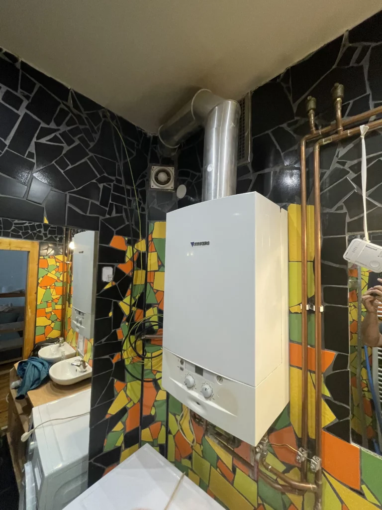 Nástěnný plynový kotel v koupelně s trubkami