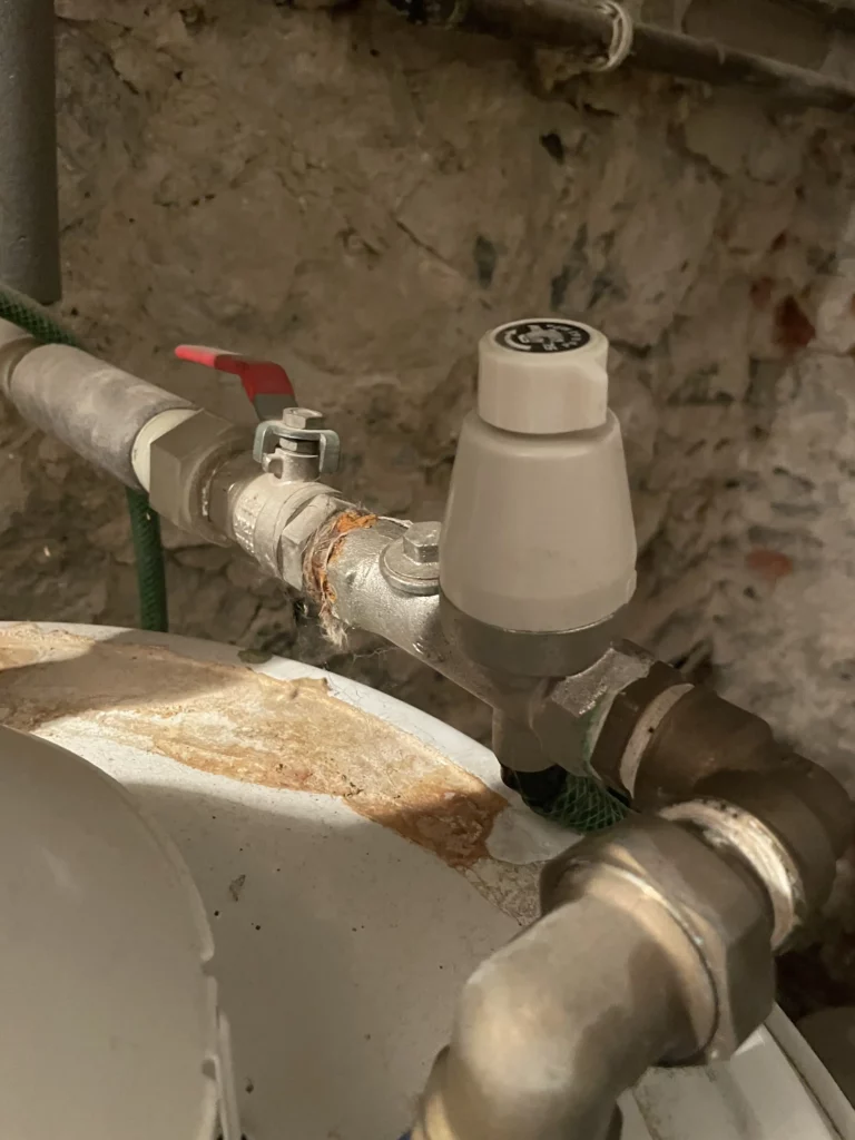 Ventil topného systému s bílou krytkou a stopami rzi