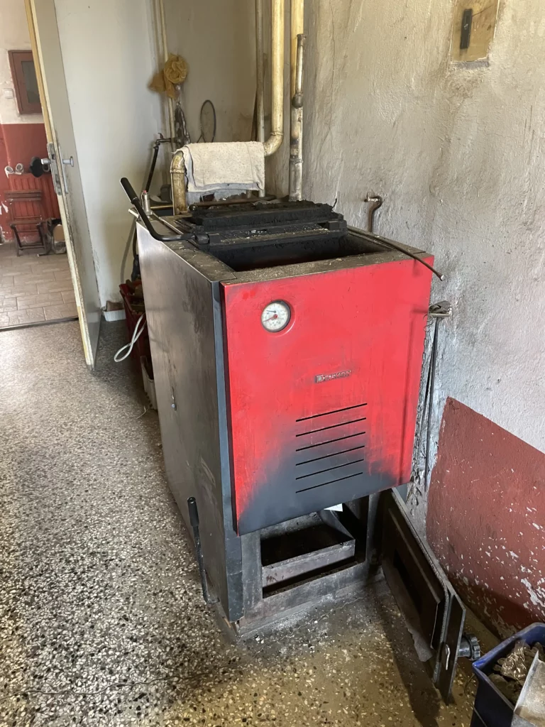 Starší červený litinový kotel v kotelně